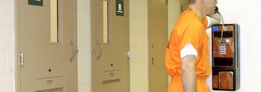 prisoner white man leaning the wall while he is calling using telephone's jail