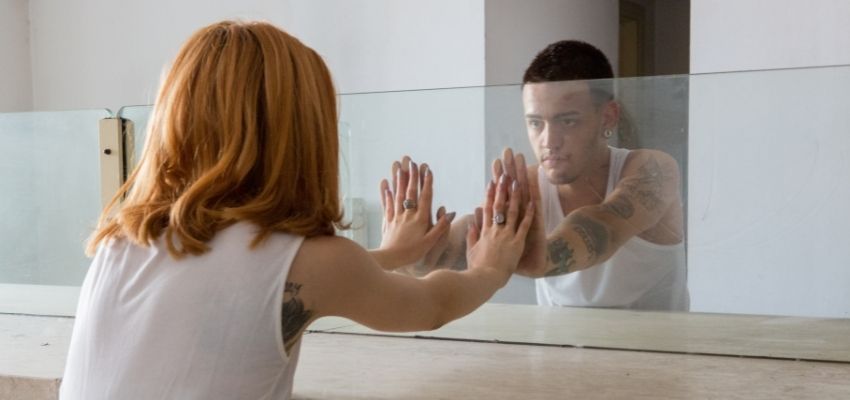 A prisoner and his wife being separated by a glass wall inside the prison visitation room.