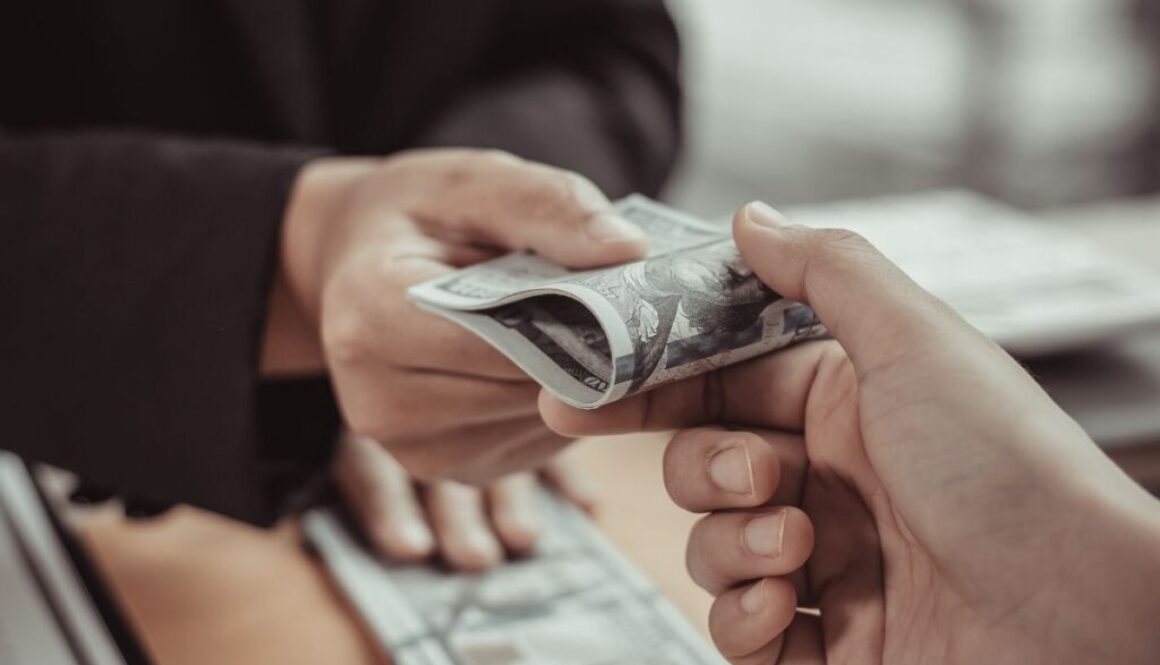 Someone giving another money in an act that can either be extortion, bribery, or quid pro quo.