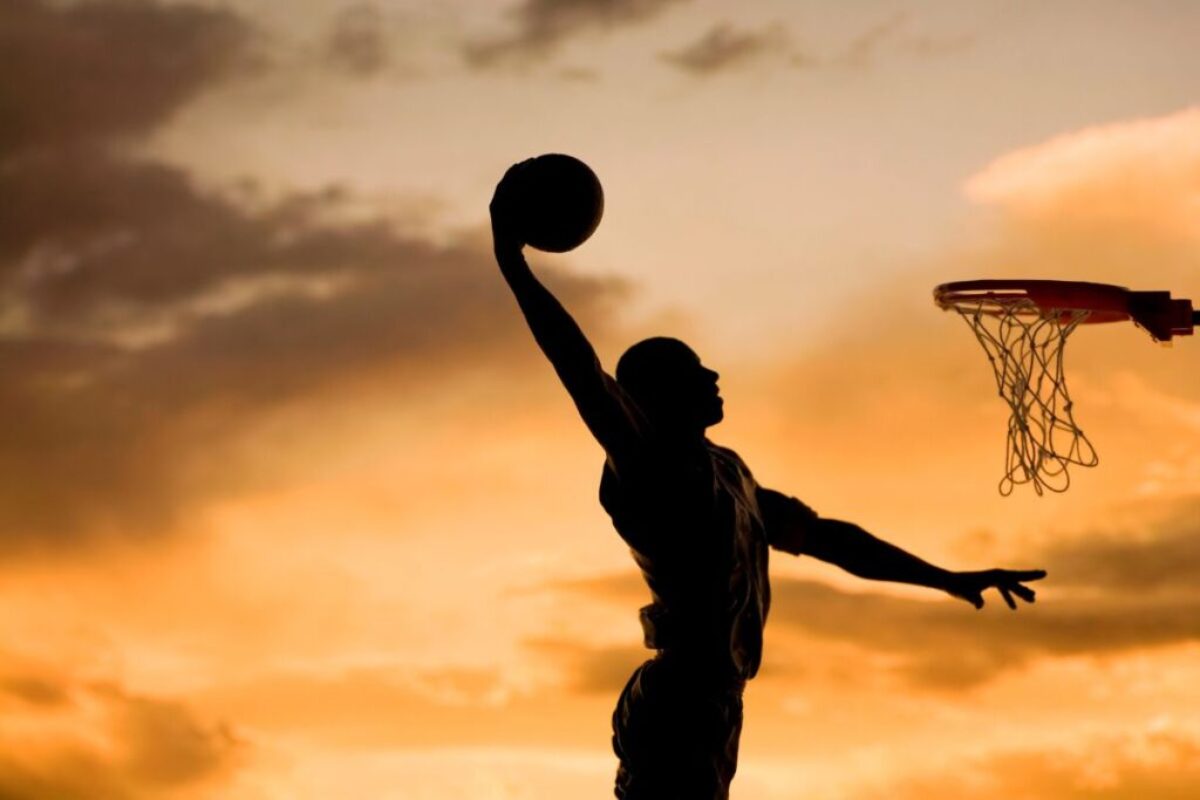 A silhouette of a man playing basketball in twilight.