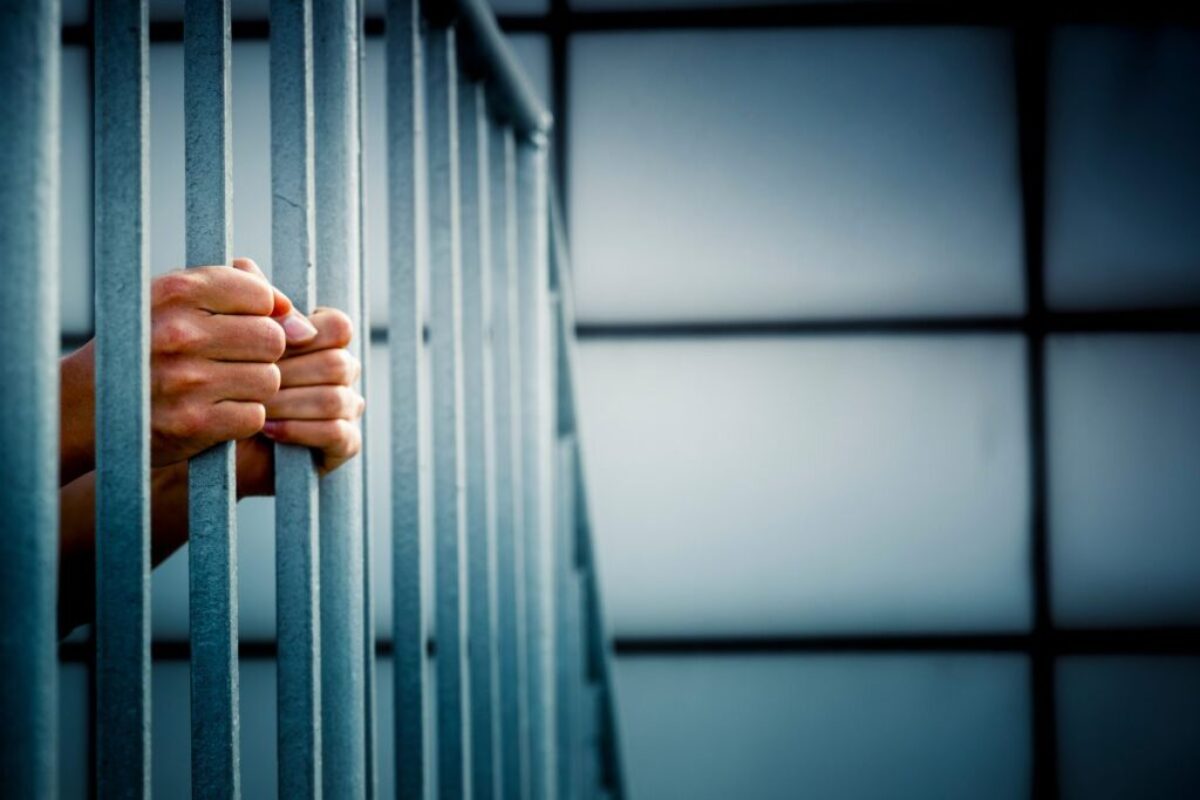 An inmate holding onto the bars on his jail cell.