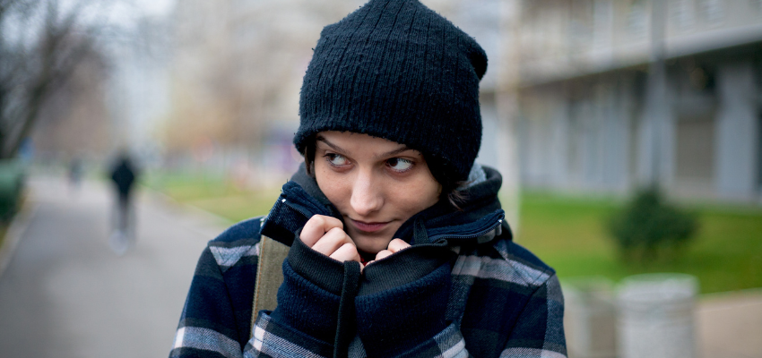 A woman pulling a scarf over her face.