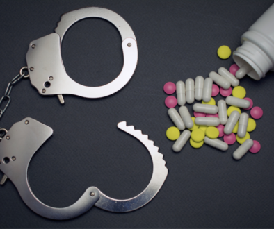 Colorful pills scattered beside an unlocked handcuff.