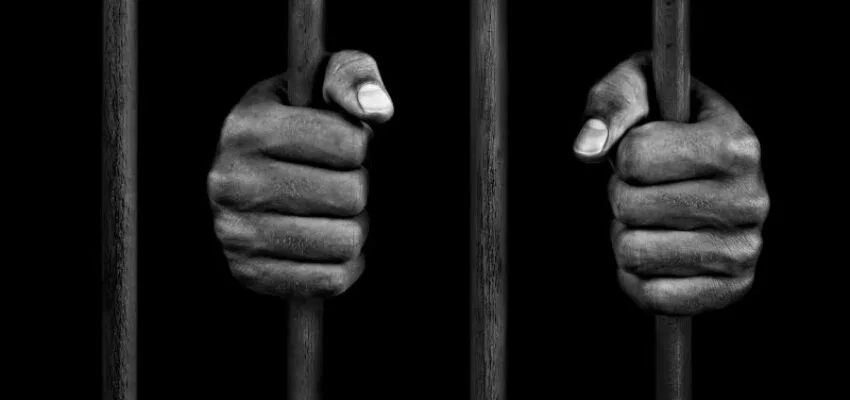 A prisoner holding the prison bars.