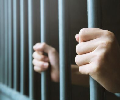 The prisoner is holding the prison bars.